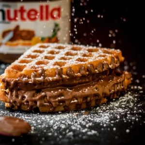 Delicious waffles with creamy chocolate hazelnut spread, topped with sugar dusting.